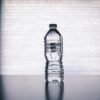 Stylish photo of a clear plastic water bottle on a reflective surface with a soft shadow.